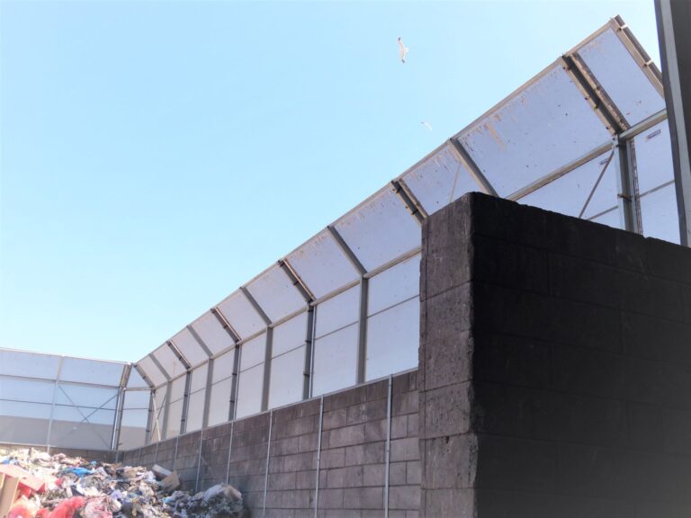 Binnenaanzicht stofmuur bij buitenopslag op recyclage site met houtschredder en zichtbare constructie