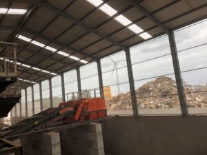 Binnenaanzicht recyclagehal met stofschermen bij houtschredder installatie