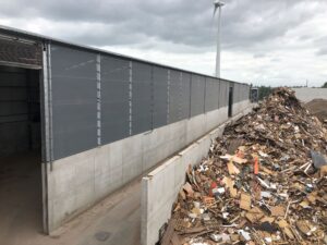 Buitenaanzicht recyclagehal met stofschermen bij houtschredder installatie